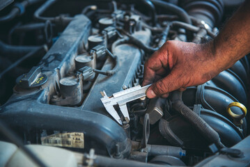 Close up Mechanic man hands repairing car auto repair shop uses jack change tyre. Man hands fixing...