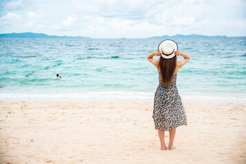 Cheerful asian woman barefoot walking on tropical summer beach. Woman walking along wave of sea...