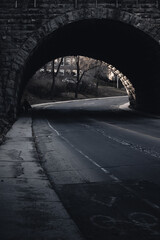 Person walks under dark bridge with tints of monochrome landscape