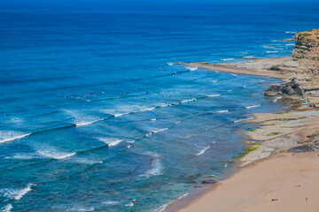 Aerial view of Ribeira d'Ilhas beach with silhouettes of surfers and boards in the sea, Ericeira - Mafra PORTUGAL