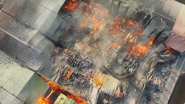 The industrial site lay in ruins, ravaged by a raging inferno. Roof sections collapsed, flames devoured structures, and smoke billowed, marking a catastrophic event.
