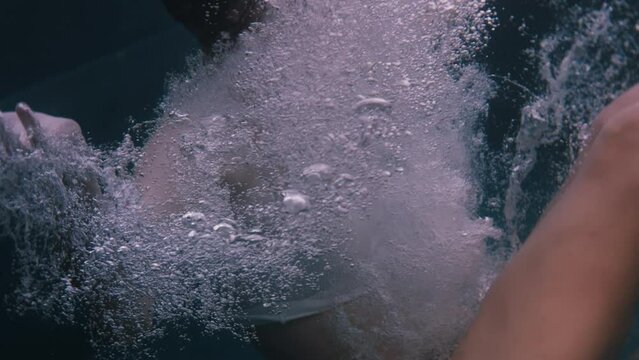 Woman falling underwater and bubbles flying around