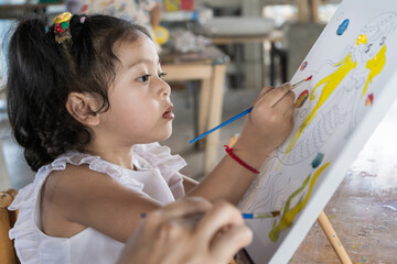  Asian beautiful baby girl drawing on canvas to create creativity happily. I