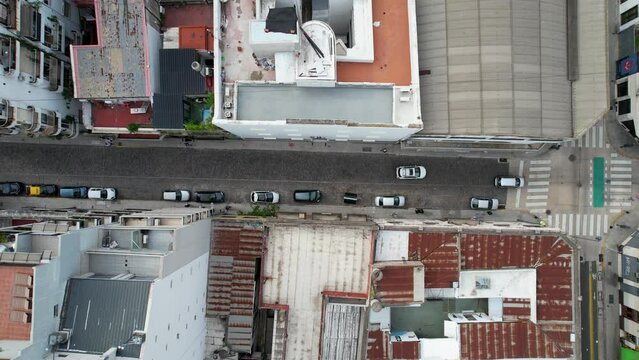 Auto blanco circula por la calle vista cenital de dron, cruce de calles, edificios.