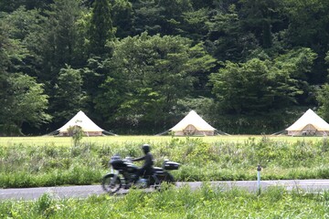 自然の中のグランピング　バイクで横切るライダー