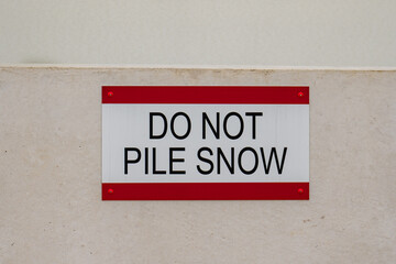 Close-Up photos of a DO NOT PILE SNOW sign on the roof of a concrete parking structure.