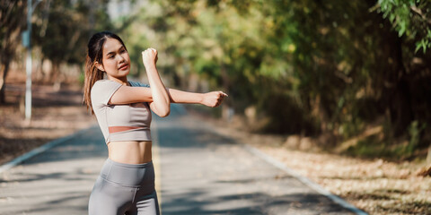 Young woman in fitness attire doing arm stretches before starting her workout on a scenic outdoor...