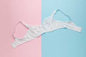 A white women's bra on a pink and blue background.