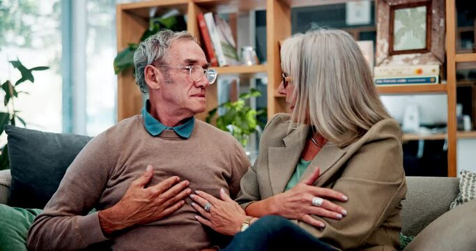 Elderly couple, sofa and chest with pain in living room for emergency, stress and heart attack. Retirement, woman and man with anxiety at home for cardiovascular fear, problem and crisis in house