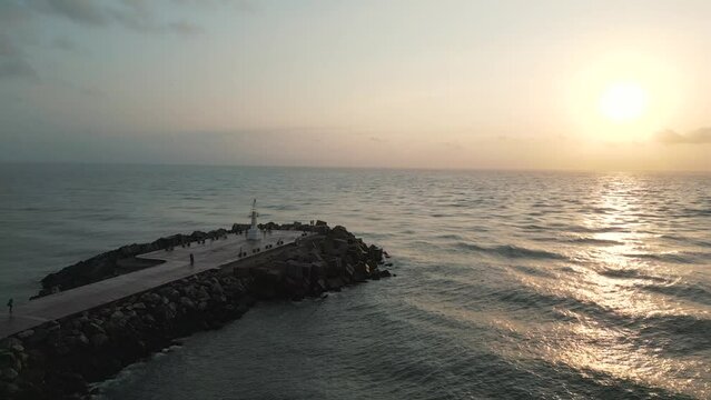 Static drone shot of the Playa Miramar Madero Lighthouse with the tranquil waters of the Gulf of Mexico in a beautiful sunset.