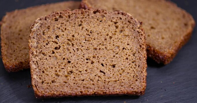sliced black bread on a black slate board, square-shaped pieces of fresh bread