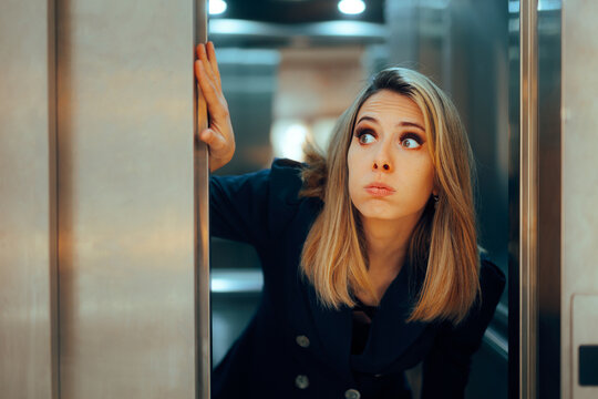 Funny Woman Holding the Elevator Door with her Hand. Anxious businesswoman feeling scared of getting trapped in small spaces 
