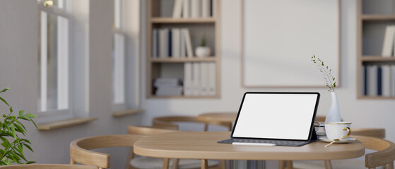 A digital tablet on a wooden table in a minimalist contemporary coffee shop or co-working space.