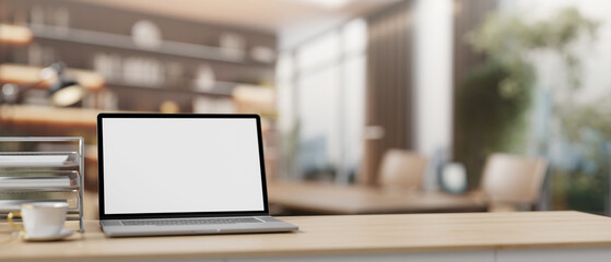 A laptop computer mockup on a table with a blurred background of a contemporary meeting room.