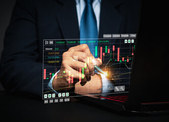Businessman or trader pointing to a graph stock on a virtual screen.