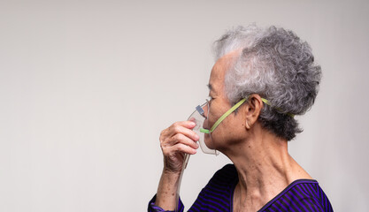 An elderly Asian woman using an oxygen mask. - obrazy, fototapety, plakaty