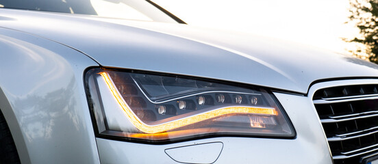 Headlight turned on in Clean car after Washing luxury silver car. Sedan car exterior of modern...