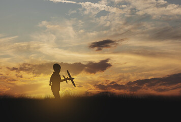silhouette boy playing toy airplane at sunrise
