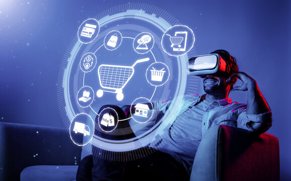 Happy man using VR headset and shopping online while sitting at sofa with shopping bags. Smart person looking at online market hologram and icon with neon background. Innovation technology. Deviation.