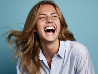 A woman with long hair is smiling and laughing while wearing color clothing