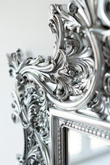 An ornate silver mirror with a detailed frame, reflecting a soft light