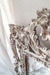 An ornate silver mirror with a detailed frame, reflecting a soft light