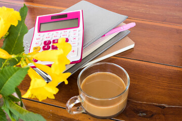 notebook planner, calculator for business work with hot coffee arrangement flat lay style on background wooden