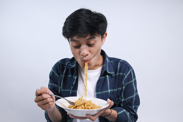 Excited Young Asian Man Eating Spicy Noodles Isolated On White Background