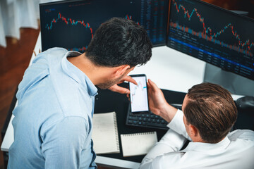 Investor stock officer focusing on dynamic exchange rate database on smartphone, comparing with...