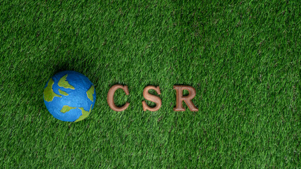 Arranged wooden alphabet text in CSR on biophilic background with Earth planet sign as eco symbol...