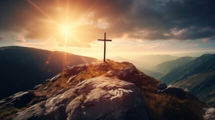 The cross on the mountain top has bright sunlight in the background.