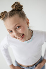 blonde girl with a playful smile shows her tongue at the camera, girl on white phoneme grimaces in front of the camera