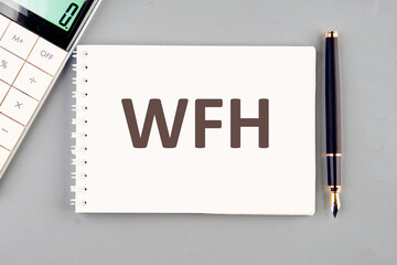 WFH Work From Home text concept. WFH written on a white notebook on a gray background