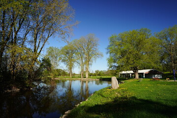 Obraz premium Grassy field park near a river reflecting the landscape.