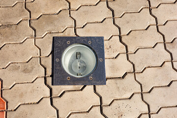 Cobblestone pavement with a round built-in lamp, night illumination of buildings, pavement light
