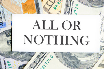 All or nothing, motivational phrase on a white business card lying on dollars