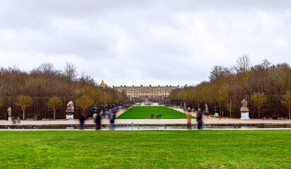 Versailles Majesty: Iconic Palace Viewed from Vast Gardens Teeming with Tourists Exploring Historic...