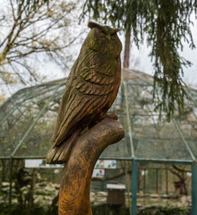 Wooden sculpture of owl on trunk. Blurred background.