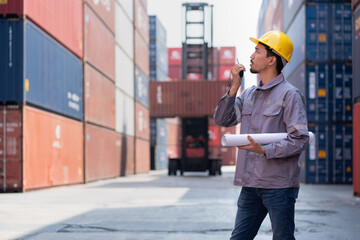 Asia logistic engineer man use walkie talkie and paper work working with forklift container...