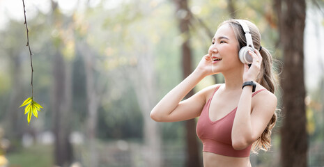 Caucasian sports woman listening to music on headphones outdoors, taking a break from her workout.