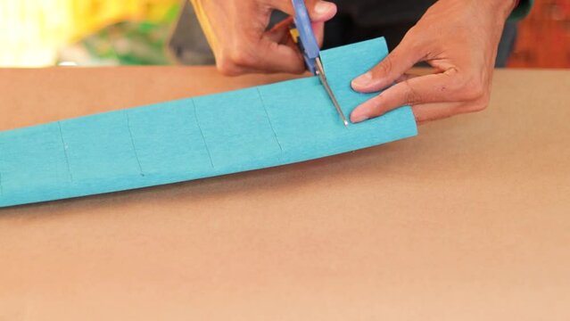 Cutting blue crepe paper as part of making a pi&ntilde;ata