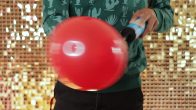 Using a manual pump to inflate a red latex balloon