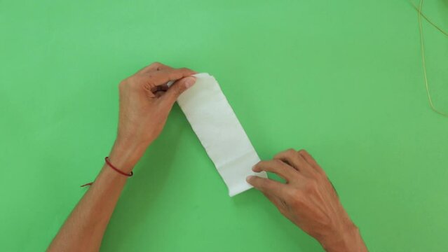 Cutting white paper and making it part of decoration for a Mexican festivity, paper strip garlands