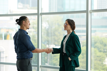 Business colleagues shaking hands on hall of office building