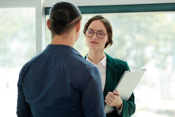 Serious entrepreneur listening to excuses of coworker who skipped daily meeting