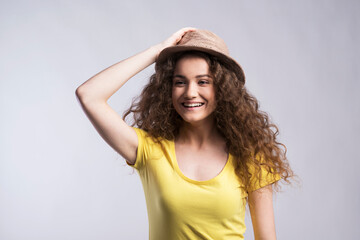 Portrait of a gorgeous teenage girl with curly hair and hat. Studio shot, white background with copy space