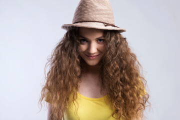 Portrait of a gorgeous teenage girl with curly hair and hat. Studio shot, white background with...