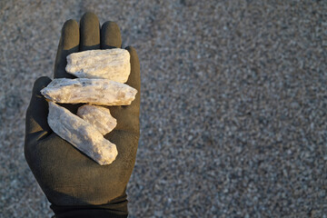 Spodumene pegmatite ore held in hand with protective glove. Commercially viable source of Lithium...