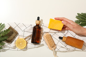 Bottles for serum, bars of soap in hand, lemon and brush on towel on  white background, top view