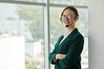 Portrait of smiling confident businesswoman wearing handsfree headset when calling coworker
